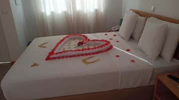 Una habitación de hotel con cama, mesita de noche y ventana con cortinas.