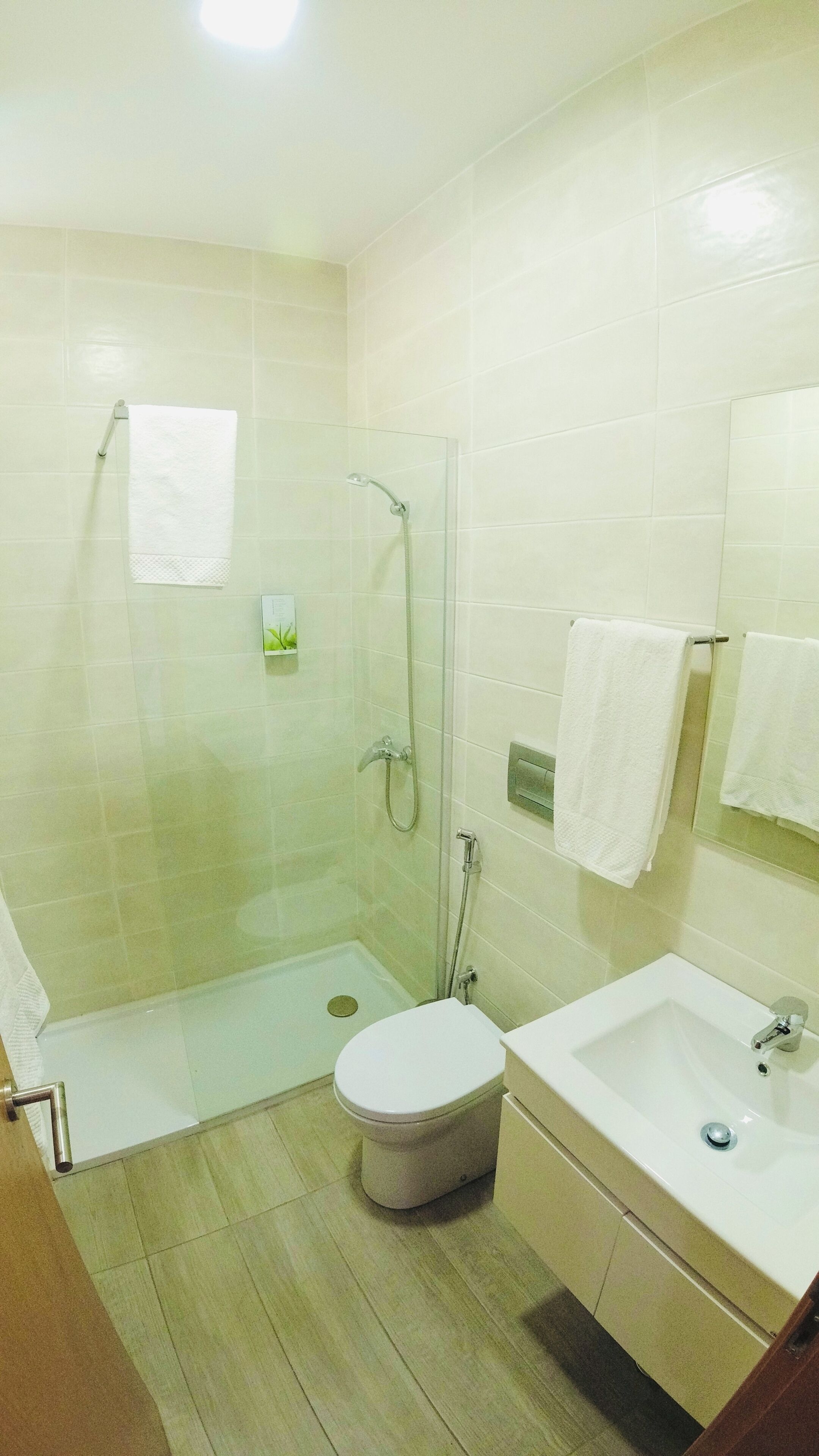 A bathroom with a shower, toilet, sink, and a mirror.