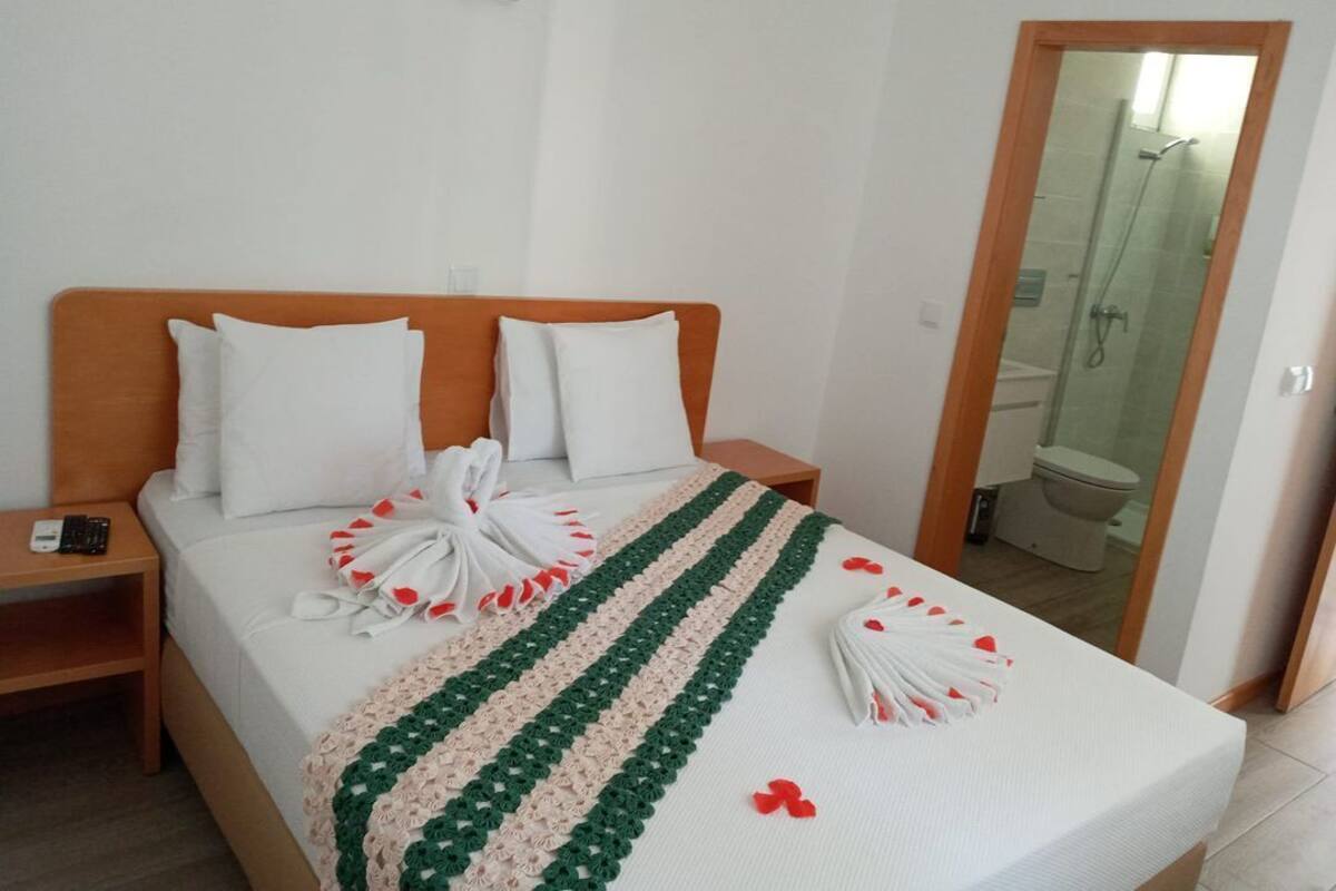 A neatly made bed with a striped blanket, a wooden headboard, and white pillows.