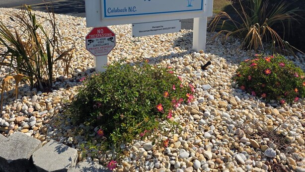 A sign for Carolina Shores Resort with a parking area and a no trespassing sign. - 2-bedroom condo in gorgeous Calabash with cool AC breeze (Calabash)