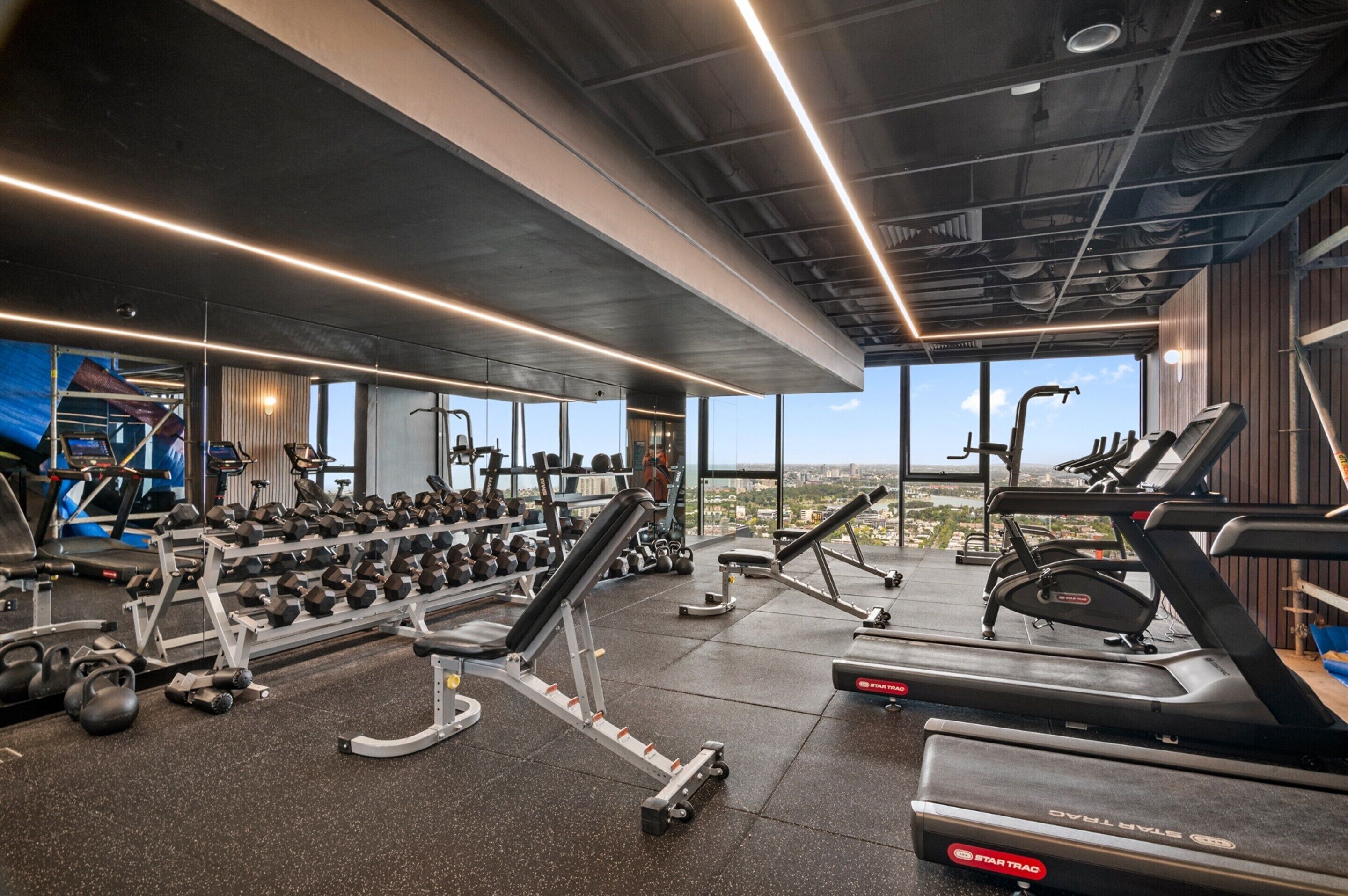 Une salle de sport équipée de tapis de course, d’haltères et d’appareils de musculation.