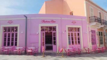 Un edificio rosa con escaparate que dice 'Stephanie Rose' y mesas con sillas para exterior.