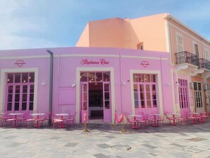 A pink building with a storefront named 'Stephanie Rose' and outdoor seating with tables and chairs. - Elysia park townhouse 14 - Modern 2 BR /Gym/ Pool/Parking/Paphos center (Pafos)