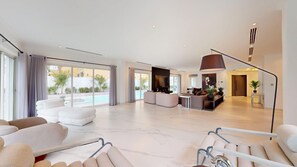 A spacious living area with a pool, modern furniture, and large windows. - Luxurious 5 Bed Villa l Private Pool, Garden (Jumeirah Park)
