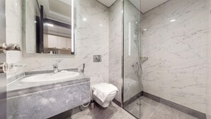 Ein modernes Badezimmer mit Marmorwaschbecken, Duschkabine aus Glas und Handtuchhalter.