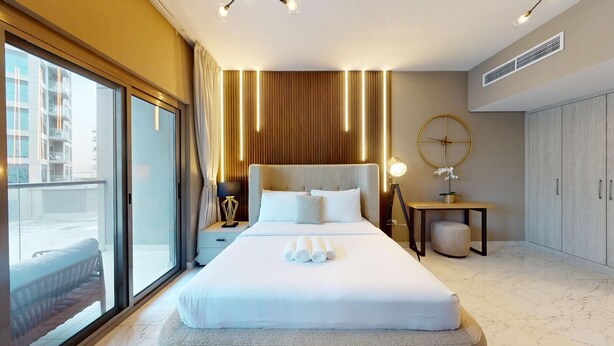 Ein Hotelzimmer mit einem großen Bett, einem Nachttisch mit Lampe, einem runden Spiegel und einem Kleiderschrank.