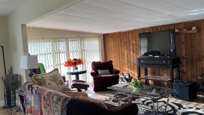 Ein Wohnzimmer mit Sofa, Sessel, Couchtisch und Fernsehschrank.