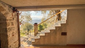 A room with a stone wall, a wooden floor, and a view of a staircase leading outside. - The Olive Grove - Sea View (Saint-André-de-la-Roche)