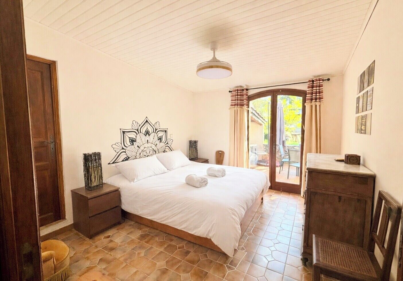 Een slaapkamer met een bed, bureau, stoel, raam met gordijnen en een deur.