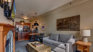 A modern living room with a grey sofa, wooden coffee table, and a TV mounted on the wall. - Palisades View One Bedroom (Olympic Valley)