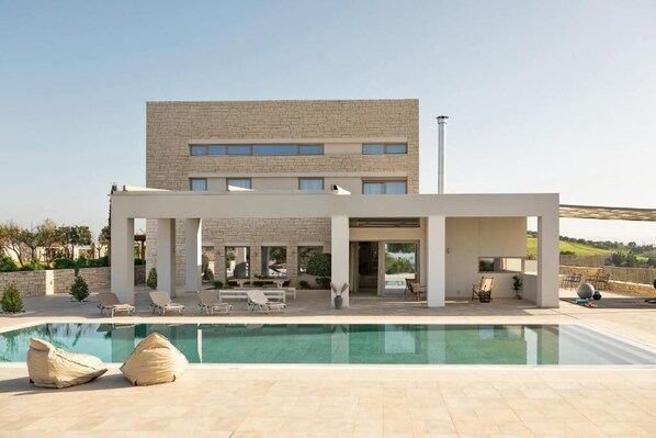 A modern building with a pool, outdoor seating, and a clear view of the surrounding landscape. - Diktamon Villa Retreat (Heraklion)