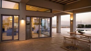 Een modern interieur met grote glazen deuren, een houten plafond en een patio met een tafel en zitplaatsen.