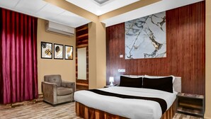 Une chambre d’hôtel avec un lit, une chaise, un bureau et un grand tableau abstrait accroché au mur.