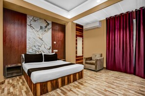 Une chambre d’hôtel avec un lit, une chaise, un plancher en bois, un mur en marbre et un rideau rouge.