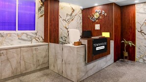 Un comptoir d’accueil au design en marbre, avec un revêtement mural en bois et une horloge.