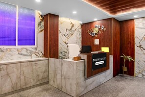 Un comptoir d’accueil au design en marbre, avec un revêtement mural en bois et une horloge.