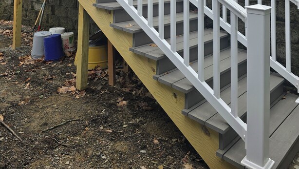 Eine Holztreppe mit weißen Geländern, die zu einem Balkon führt.