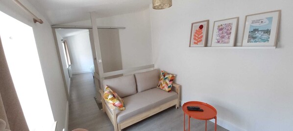 Una habitación con sofá, una mesita y una puerta que da a otra estancia.