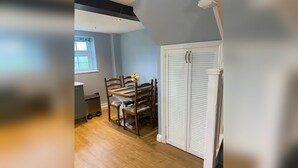 A room with a dining table, chairs, a window, and a white closet. - The Snug - Newly Renovated Charming 1769 Cottage Escape in the Countryside. (Falfield)