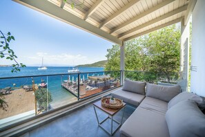 A balcony with a view of the sea, a wooden deck, and a sofa with cushions. - Orkide Bodrum (Bodrum)