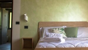 A bedroom with a wooden bed, a green wall, and a wooden ceiling. - B&B La Casetta (Verbicaro)