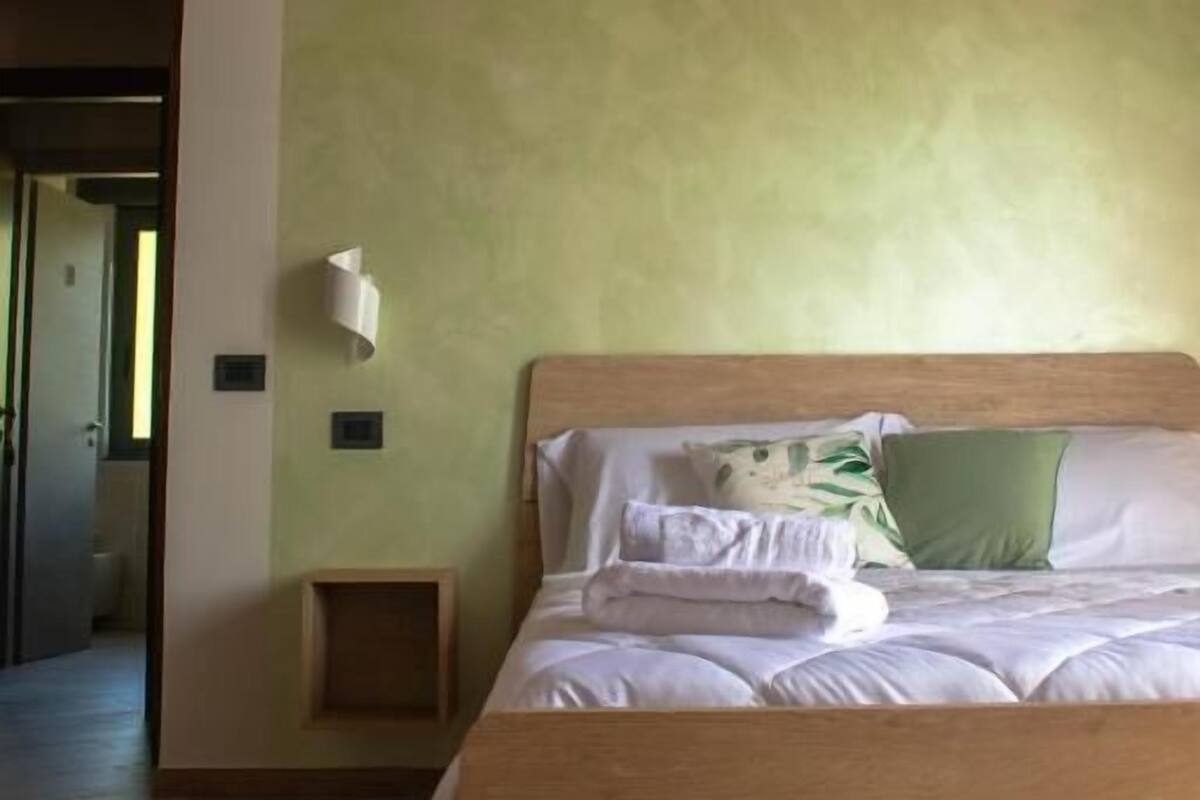 Une chambre avec un lit en bois, un mur vert et un plafond en bois.