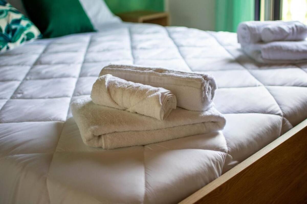 Un lit bien fait, avec une couette blanche et deux serviettes pliées posées sur le dessus.