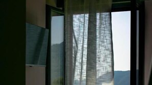 A room with a large window, a bed, and a wall-mounted air conditioning unit. - B&B La Casetta (Verbicaro)