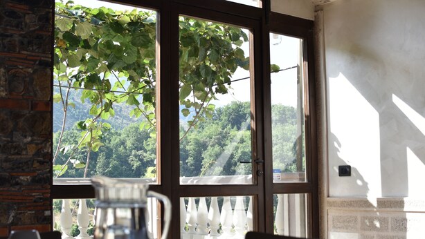 A dining area with a view of a lush green landscape through large windows. - B&B La Casetta (Verbicaro)