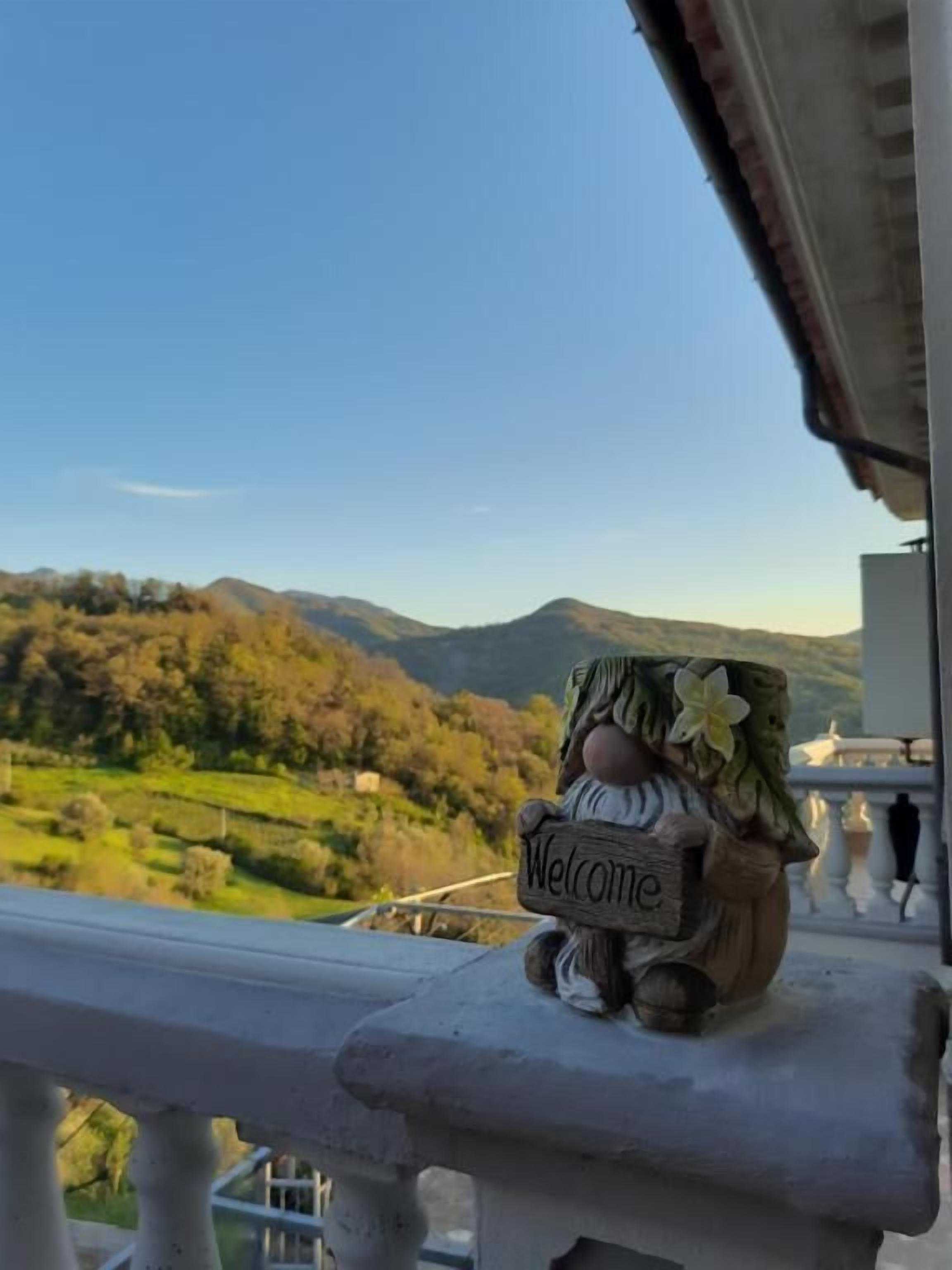 A decorative welcome sign on a balcony railing overlooking a mountainous landscape.