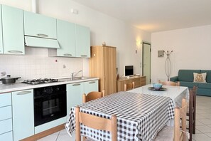 Une cuisine de taille réduite comprenant une table à manger, une cuisinière et un meuble en bois.