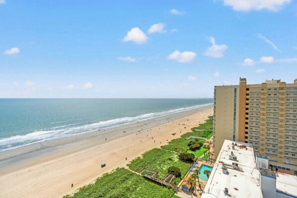Een uitzicht op het strand met een hotelgebouw naast de kust.