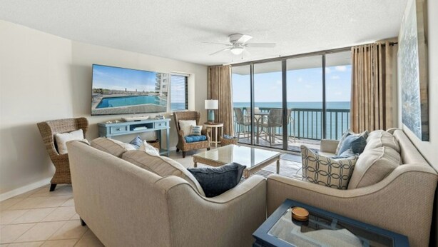 A hotel room with a sofa, a coffee table, a TV, and a balcony with a view of the sea. - Ocean Bay Club 1510-4 Bedroom-Indoor/Outdoor Pools (North Myrtle Beach)