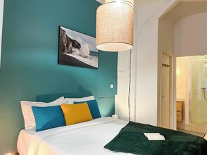 Une chambre à coucher avec un lit, une lampe suspendue, un tableau et un espace douche.