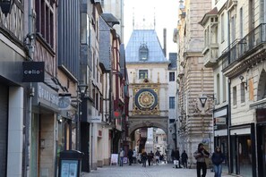 Een historische straat met een opvallende klokkentoren, geplaveid met kinderkopjes en diverse winkelgefaciliteiten.