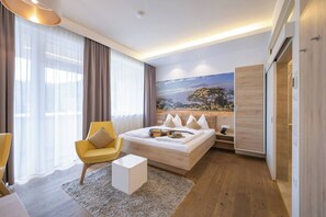 A modern hotel room with a large bed, a yellow armchair, a small white table, and a painting of a landscape on the wall. - Brightside Studio I Graz-süd I for 2 24-7 Check-in (Graz)