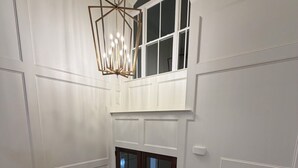 Habitació amb escala de fusta, un penjador, una llar de foc i una finestra amb vista.