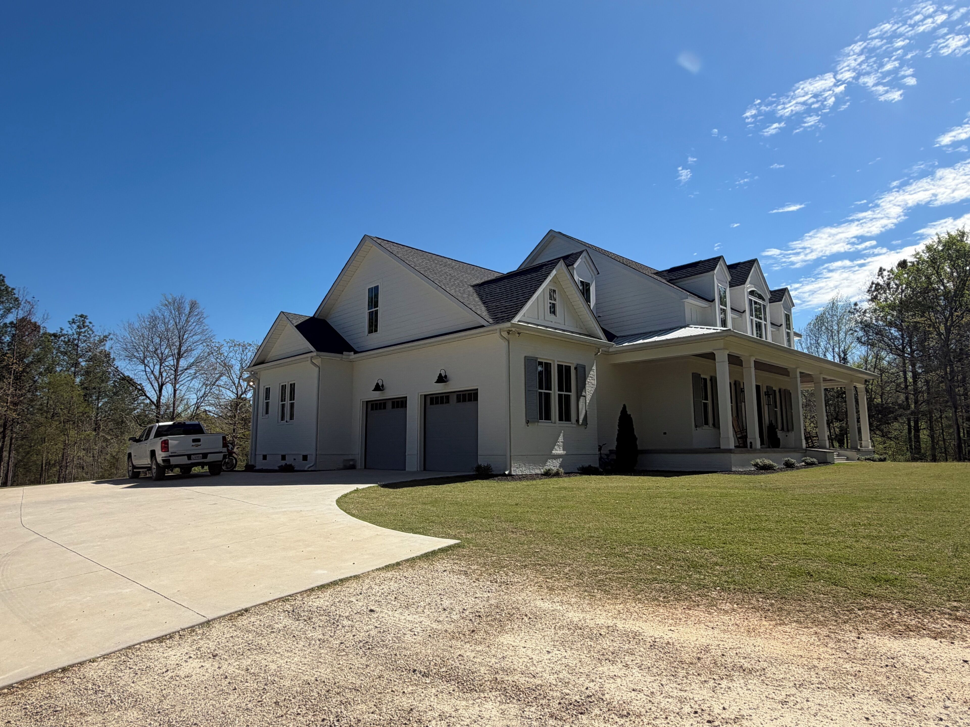 A large, single-story house with a covered porch, a driveway, and a well-maintained lawn.