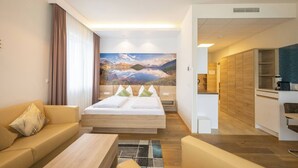 A modern hotel room with a bed, sofa, and kitchenette. - Suite With Character I Graz-süd for 2 24-7 Check-in (Graz)