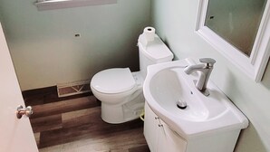 A bathroom with a toilet, sink, and window. - Lake Erie Fisherman’s Retreat – 3BR Home in Vermilion with boat parking space. (Vermilion)