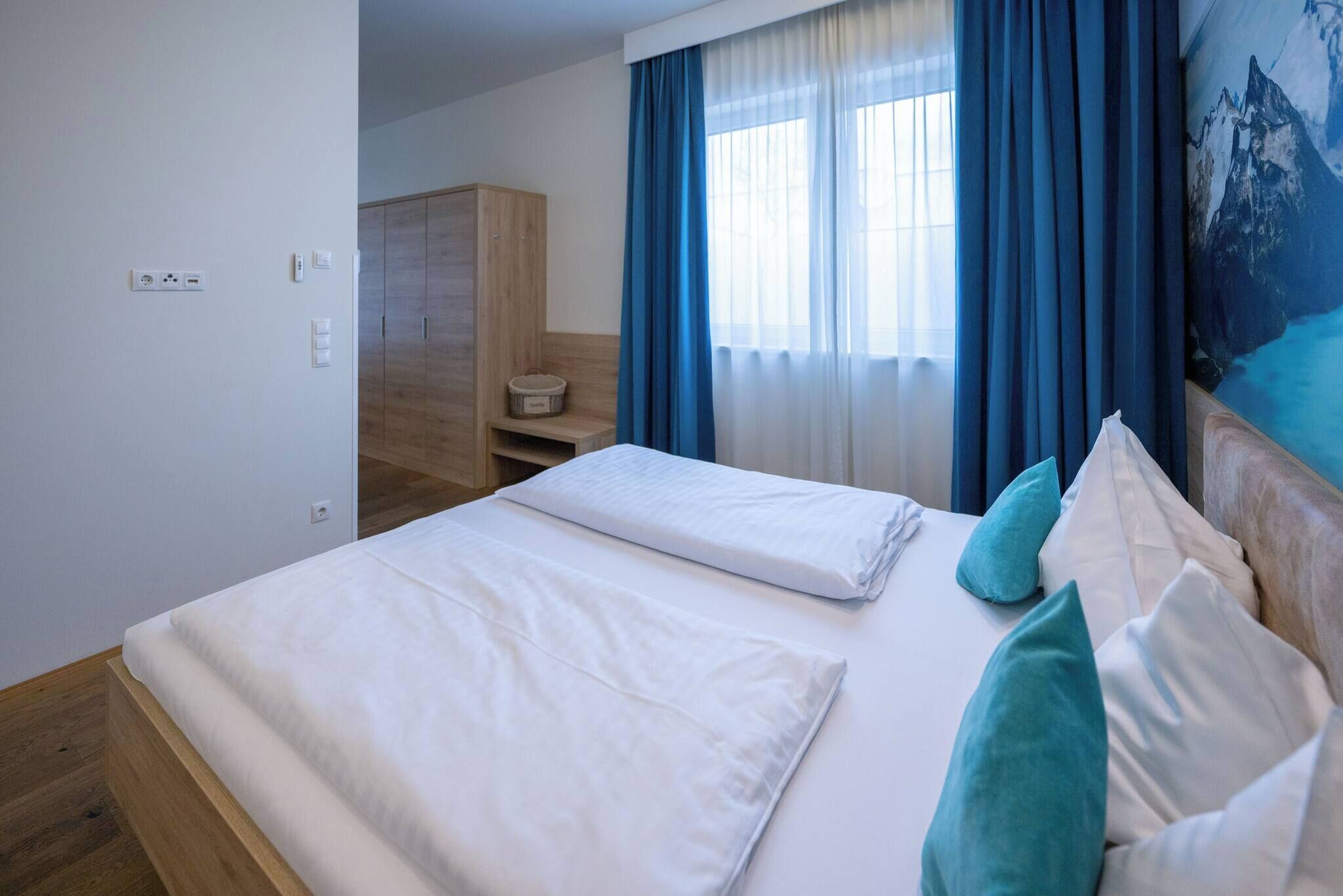 Una camera d'albergo con un letto, un armadio, un tavolino e un quadro appeso al muro.