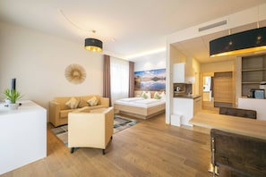Ein modernes Hotelzimmer mit einer Couch, einem Bett, einem Essbereich und einer Küche.