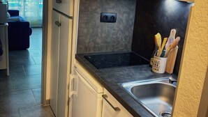A compact kitchen with a built-in stove, a sink, and cabinets. - Studio by the sea with pool (Le Grau-du-Roi)