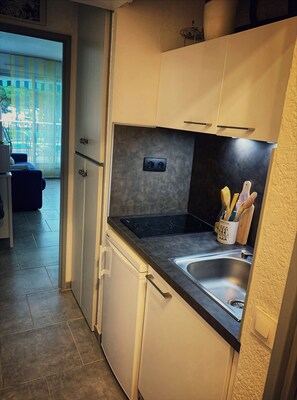 A compact kitchen with a built-in stove, a sink, and cabinets. - Studio by the sea with pool (Le Grau-du-Roi)