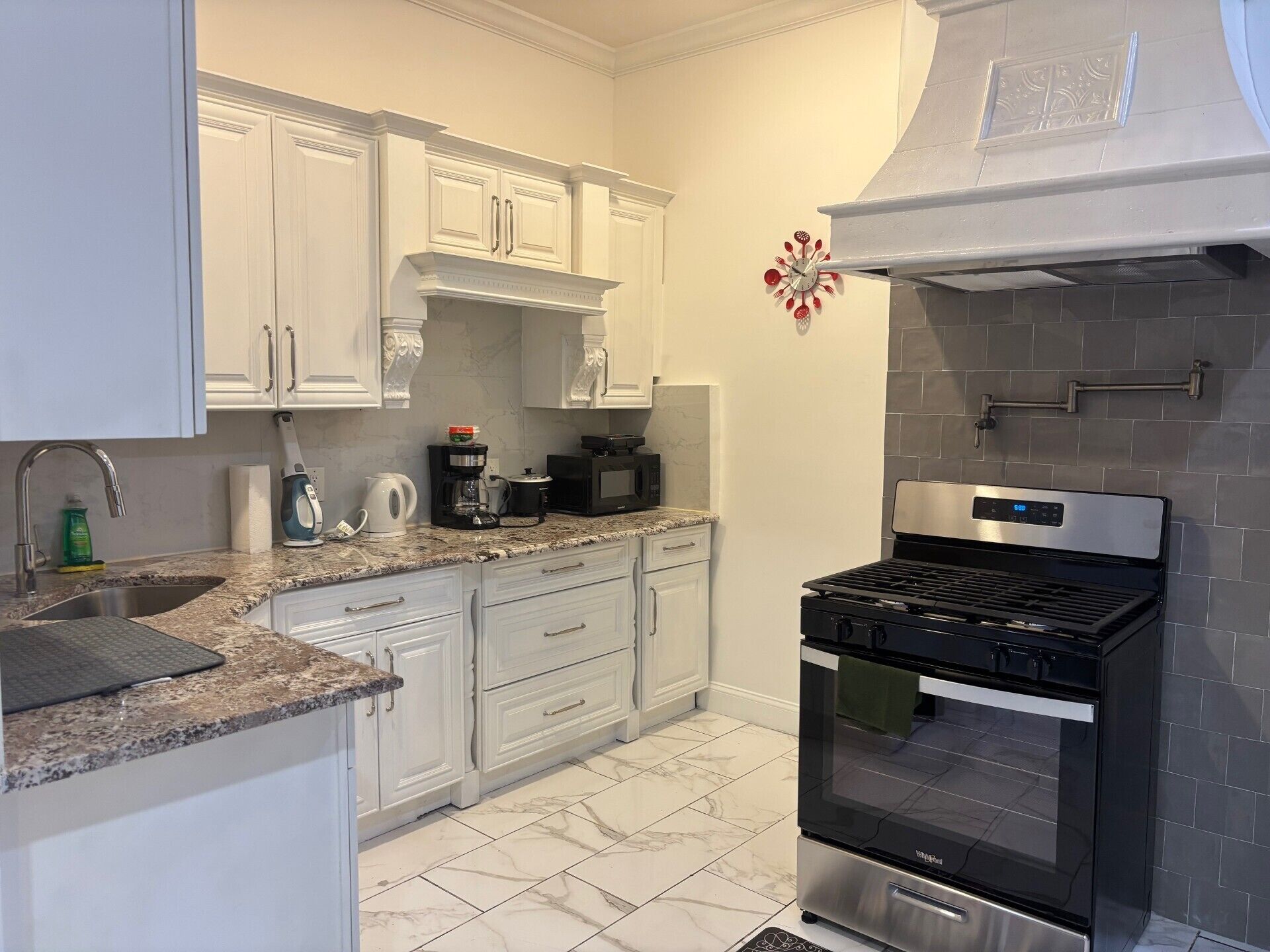A kitchen with white cabinets, a stainless steel oven, a coffee maker, and a microwave.