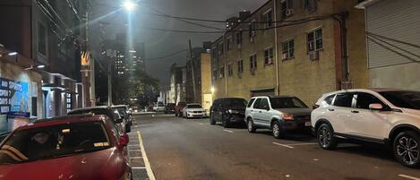 A nighttime street scene with parked cars and buildings.