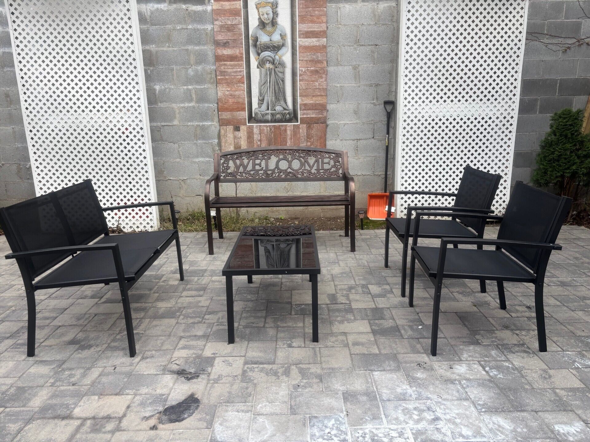 Un patio con un banco, dos sillas y una pequeña mesa.