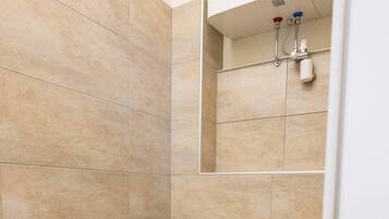 Un baño con baldosas color beige, inodoro, bidé y panel de control de ducha.