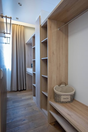 Un pasillo con estanterías de madera, una cesta de mimbre con la etiqueta 'Dess&Das' y una puerta con cortina.