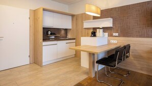Een moderne keuken met houten kastjes, een inbouwfornuis, een koffieapparaat en een eethoek met een tafel en stoelen.